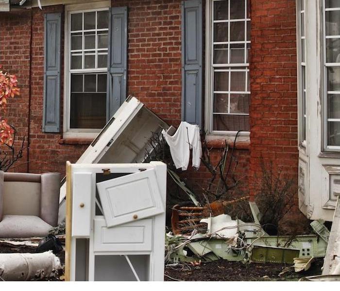 damaged furniture and other home items sitting outside of red brick house
