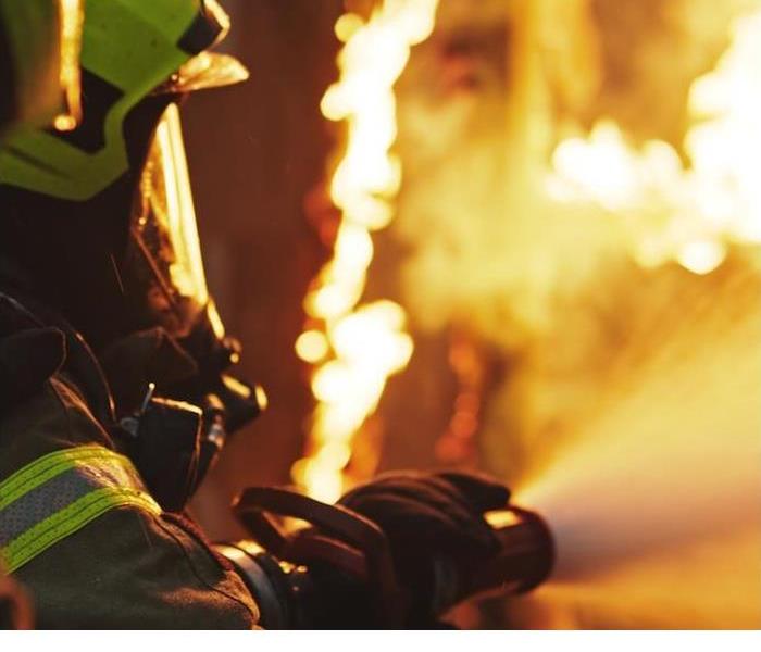 img src =”firefighter.jpg” alt = "a firefighter battling a fire with a water hose in hand” >