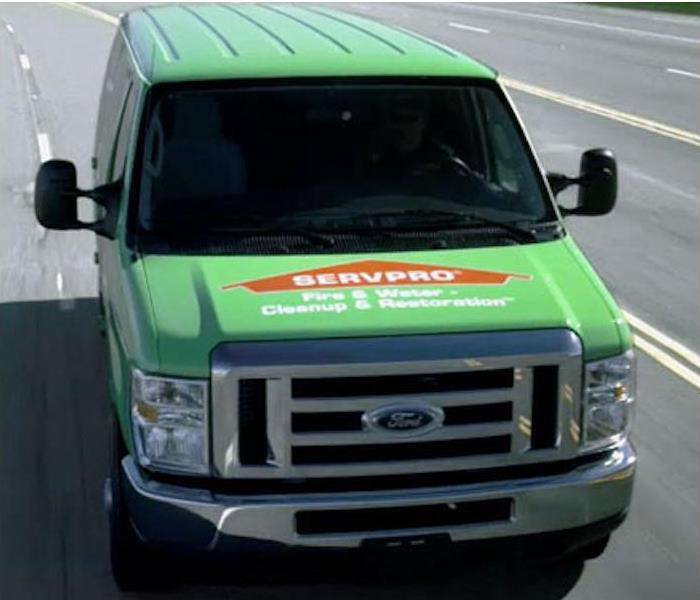 SERVPRO van lime green with orange parked on a street on a sunny day 