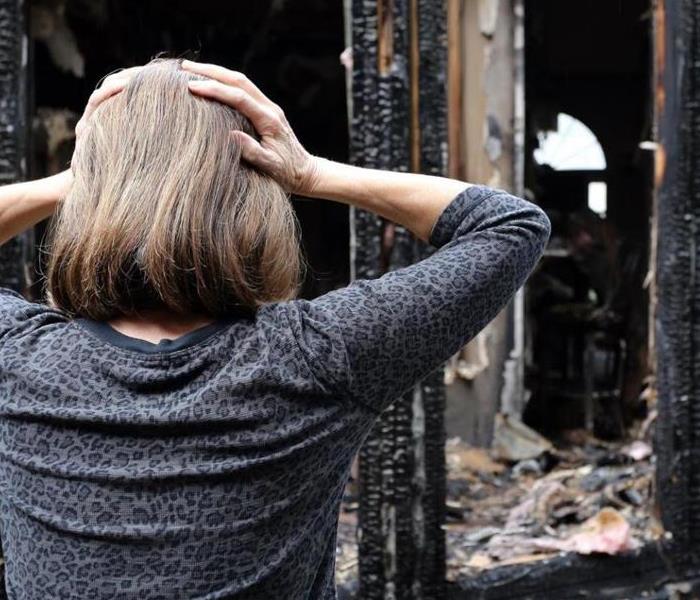 Woman standing looking at fire damaged home 