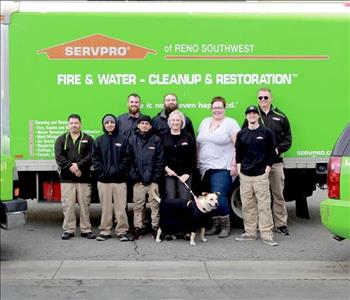 SERVPRO green box truck with all the crew standing directly in front with a dog 